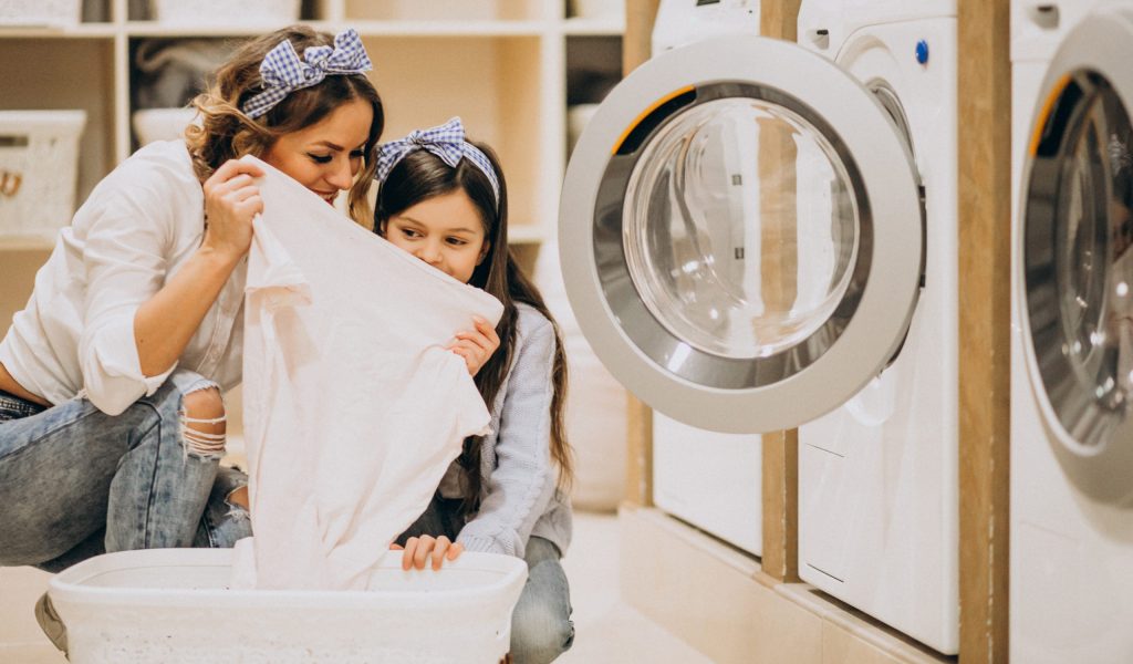 Mother with daughter doing laundry at self serviece laundrette